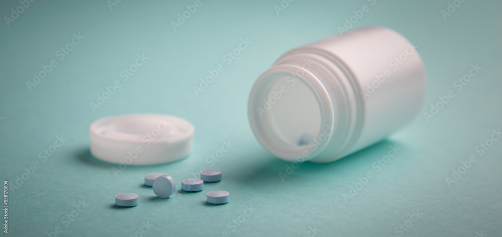 group of pills out of the bottle, on a blue colored surface group of pills out of the bottle, on a blue colored surface