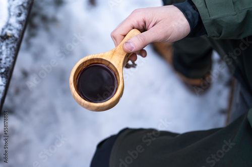 Man holding a Finnish wooden cup, kuksa, with coffee in it. Finland photo