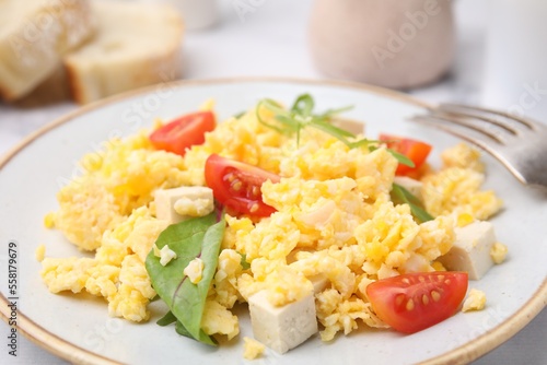 Plate with delicious scrambled eggs, tofu and tomatoes on table, closeup