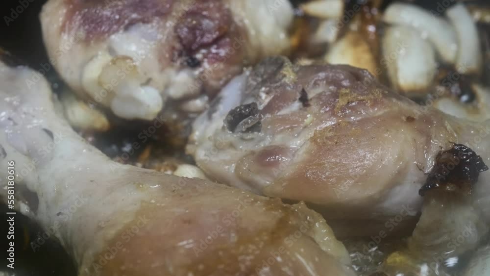 chicken drumsticks fried in sunflower oil with onion and garlic in a pan, macro chicken drumsticks fried in sunflower oil with onion and garlic in a pan, macro