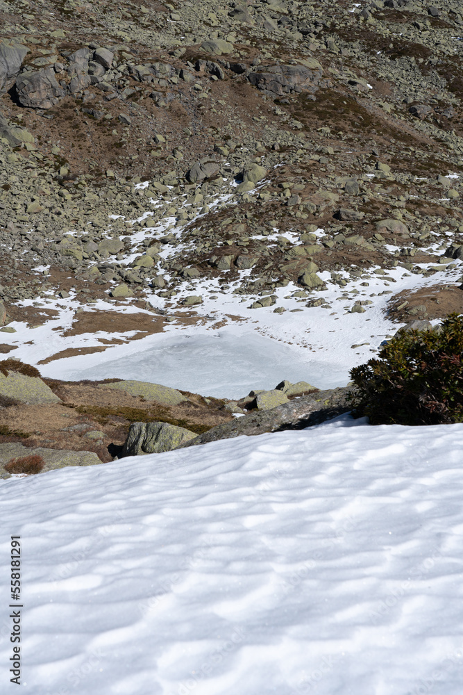 mountain frozen lake in the alps, snow around the lake and rocky background mountain frozen lake in the alps, snow around the lake and rocky background