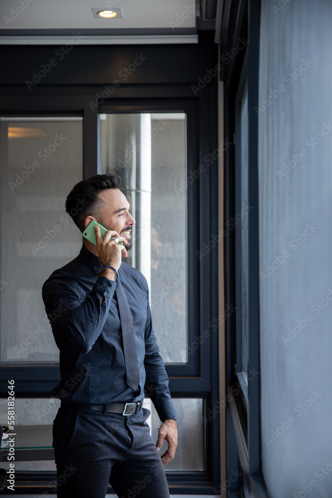 Handsome businessman in black suit talking on the phone in the office Handsome businessman in black suit talking on the phone in the office