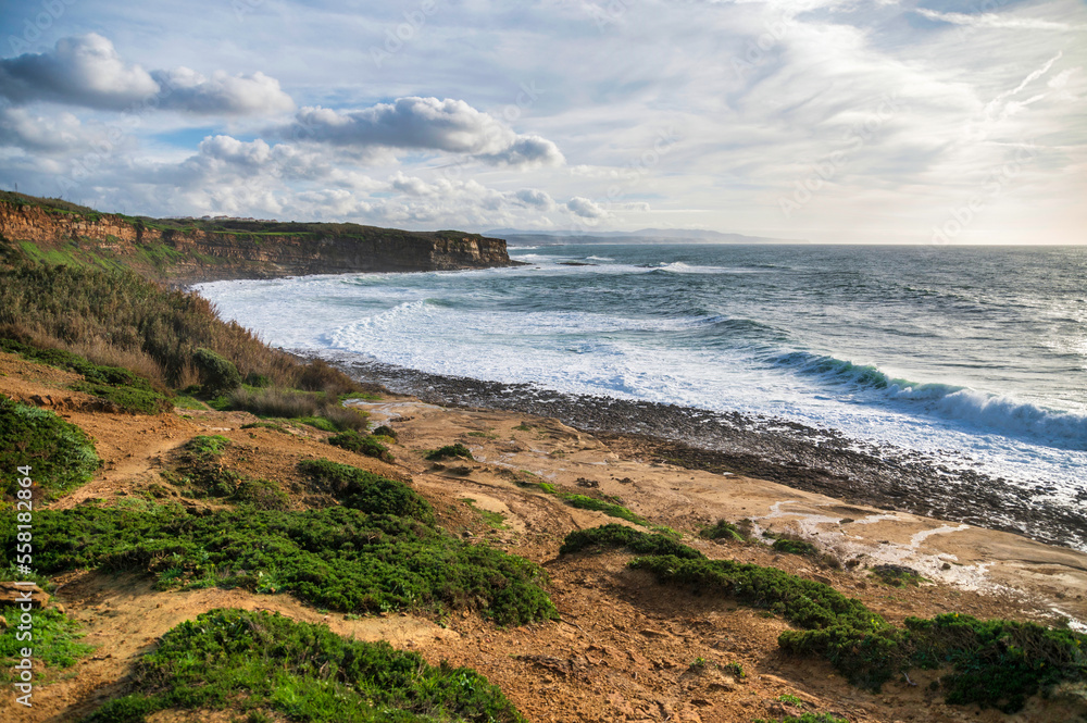 A powerful ocean wave crashes and breaks, creating foamy white spray as it approaches a rocky shoreline. A powerful ocean wave crashes and breaks, creating foamy white spray as it approaches a rocky shoreline.