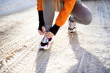 Woman tying shoe at winter before running