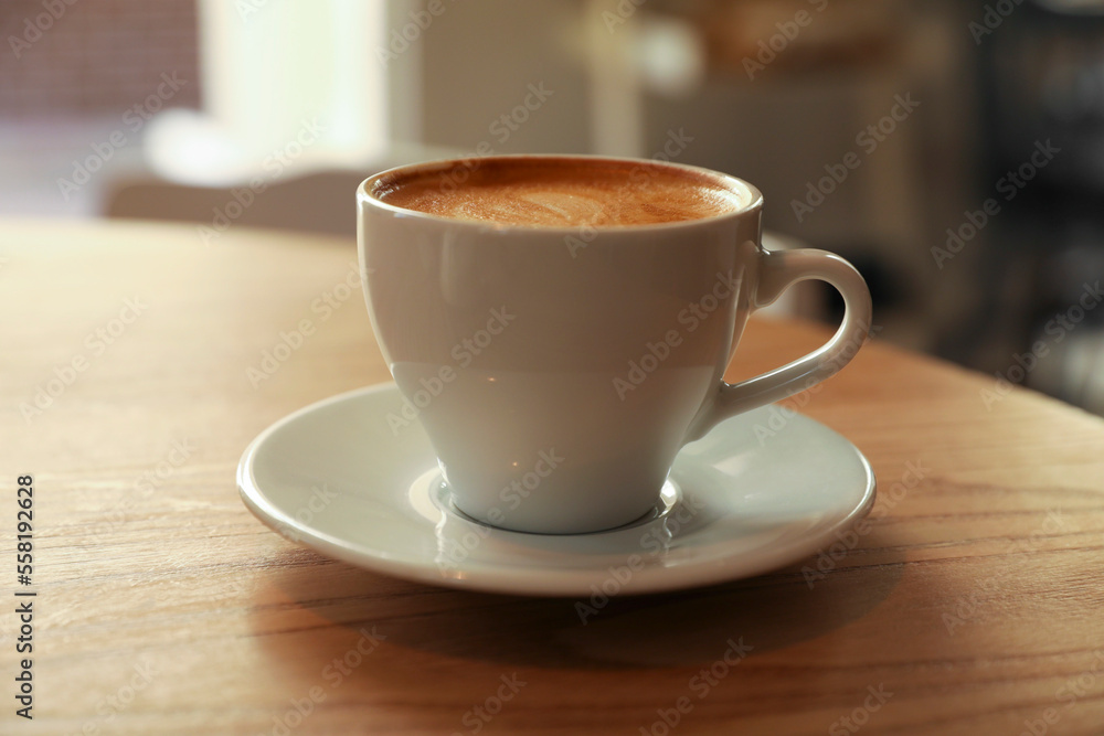 Cup of aromatic hot coffee on wooden table in cafe, closeup Cup of aromatic hot coffee on wooden table in cafe, closeup