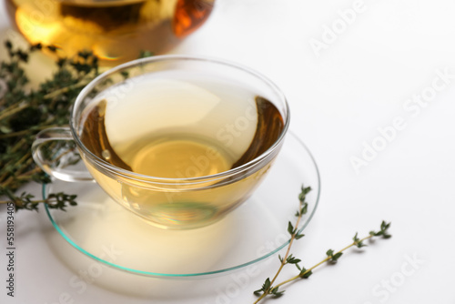 Cup of aromatic herbal tea with thyme on white table