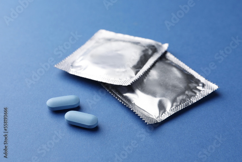 Pills and condoms on blue background. Potency problem