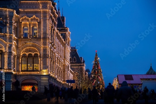 Large illuminated building of GUM with lighted decorated giant christmas tree.Christmas decorations on a facade, big xmas tree with balls and presents, city night illumination.