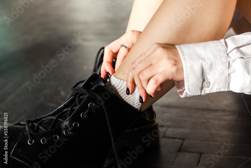 A girl in black shoes corrects her white socks.