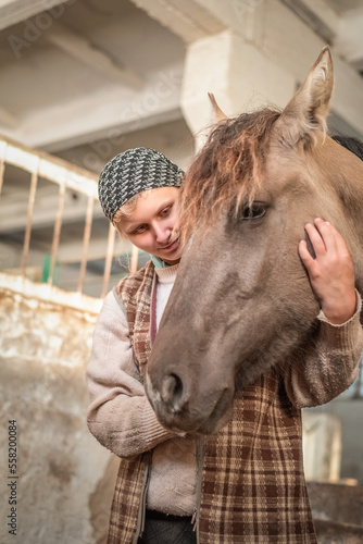 Portrait of a young beautiful girl on a farm in a stable with a horse.