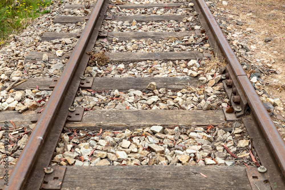 Photograph of old and rusty and out of service railway tracks with white stones and dead weeds Photograph of old and rusty and out of service railway tracks with white stones and dead weeds