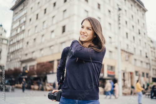 Young tourist photographer in european city exploring. Influencer on tour. Street photography lifestyle. Urban traveler on vacation. New modern profession. Content creator. Optimistic young woman