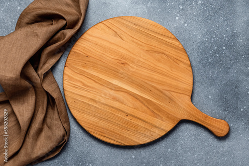 Round empty wooden charcuterie serving board with handle on old gray concrete background, shabby table. Top view. Food template with copy space. Flat lay design, mockup. Layout, cooking concept, frame