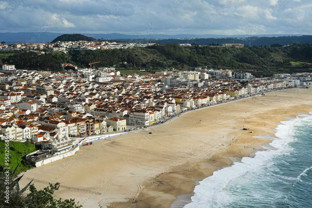 Nazare, Portugal - 30.12.2022: Breathtaking view of the small tourist town of Nazare, Portugal. View from above on small town, deserted beach and the Atlantic Ocean