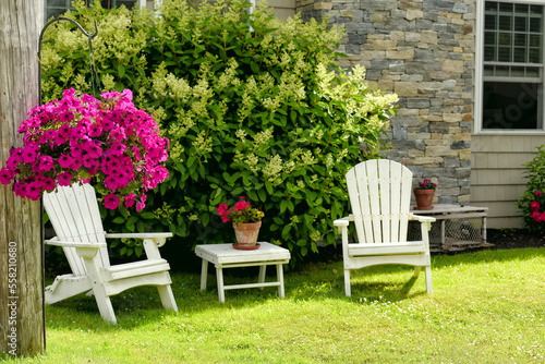 Resting place in the garden near the house. Traditional wooden armchairs and flowers. Selective focus on flowerpot with petunia flowers. © Ann Stryzhekin