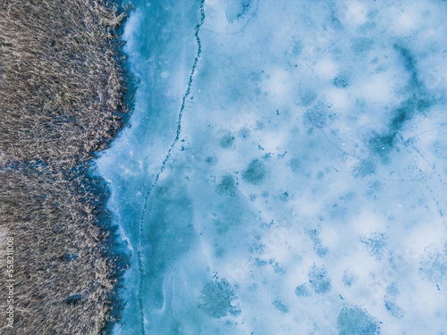 Fototapeta Naklejka Na Ścianę i Meble -  Aerial view of a frozen lake. Ice sheet background. Frozen waves on the lake. Ice background. Ice cover on a lake in southern Poland in the Bieszczady Mountains