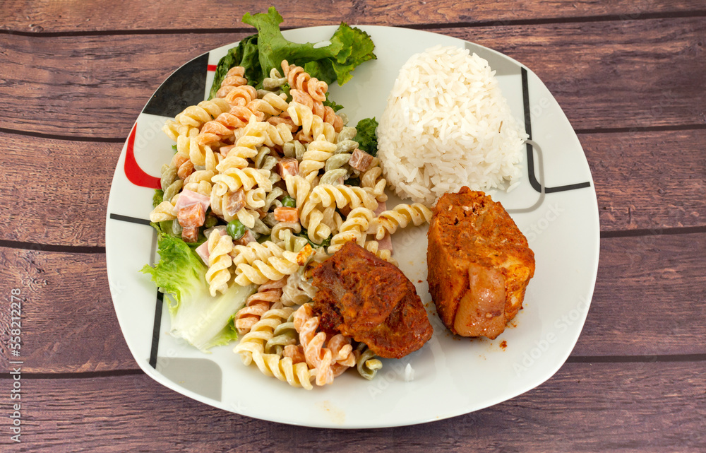 Baked pork in pieces, with lettuce, white rice and colored screw noodles Baked pork in pieces, with lettuce, white rice and colored screw noodles