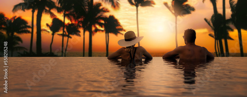 Obraz na płótnie couple enjoying sunset from infinity pool at tropical island resort hotel