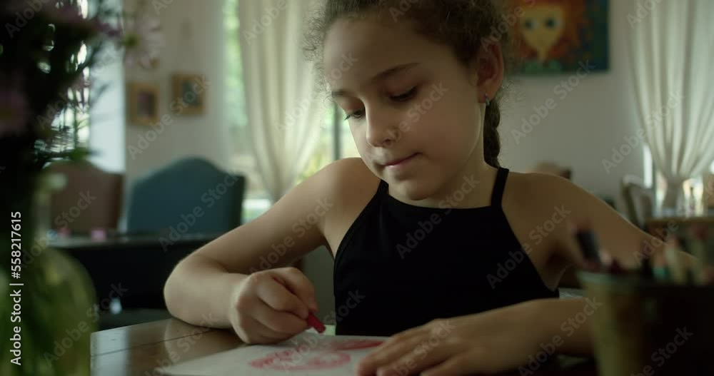 Smart primary school child drawing sit at home table. Caucasian kid drawing at home. Happy child school girl 10 years old relaxing at home, sitting at home and drawing on paper with colored pencils.