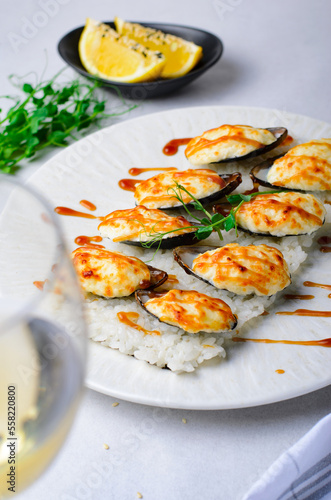Baked mussels with cheese in shells on rice in a plate