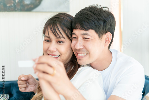 marriage couple cuddle having pregnancy test on couch. happy family want to have a cute beautiful baby. good boyfriend and girlfriend are about to be good father and mother after wife is pregnant