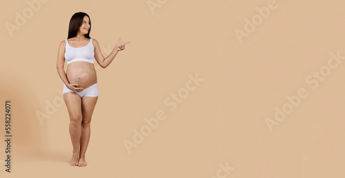 Great Offer. Happy Young Pregnant Female In Underwear Pointing Aside At Copy Space © Prostock-studio