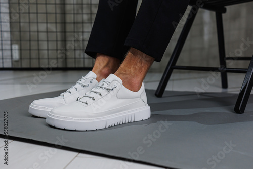 Obraz na płótnie Male legs in black pants and white casual sneakers. Men's fashionable shoes w salonie