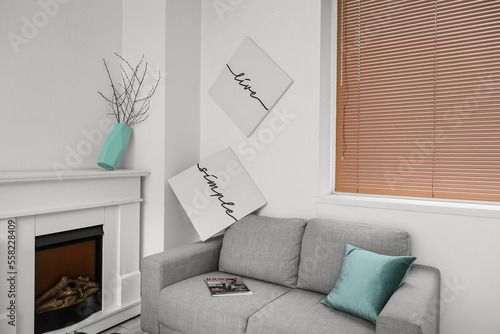 Fototapeta Naklejka Na Ścianę i Meble -  Sofa, modern paintings and fireplace in messy living room interior