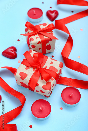 Gifts with candies, ribbon, candles and hearts on blue background. Valentine's Day celebration