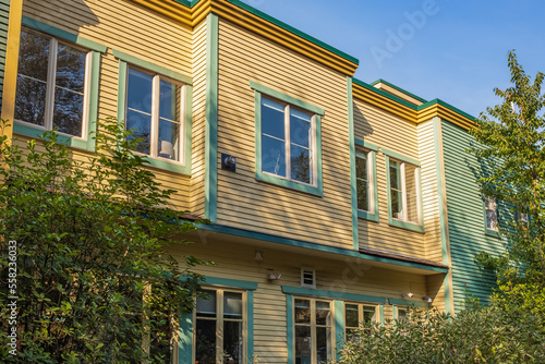 Part of the facade of a low rise wooden house with windows. Exterior of