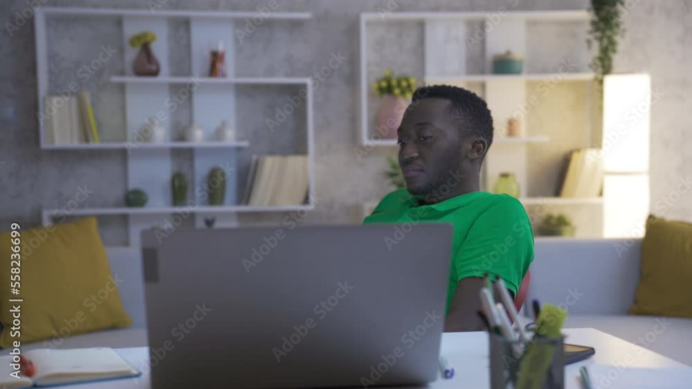 Tired African man works in his home office and his White teen girlfriend gives him morale and support. Tired African man works in his home office and his White teen girlfriend gives him morale and support.