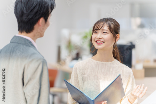 Фотография オフィスで立ち話をする若い男女