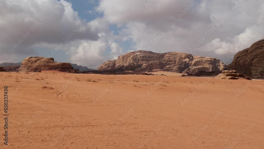 Panoramic view of Wadi Rum desert in Jordan with clouds moving over flat sand landscape with mountains in background, Panoramic view of Wadi Rum desert in Jordan with clouds moving over flat sand landscape with mountains in background,
