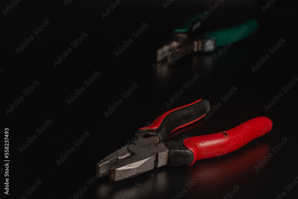 Pliers Open metal nippers with a red and green handle isolated on black background Pliers Open metal nippers with a red and green handle isolated on black background