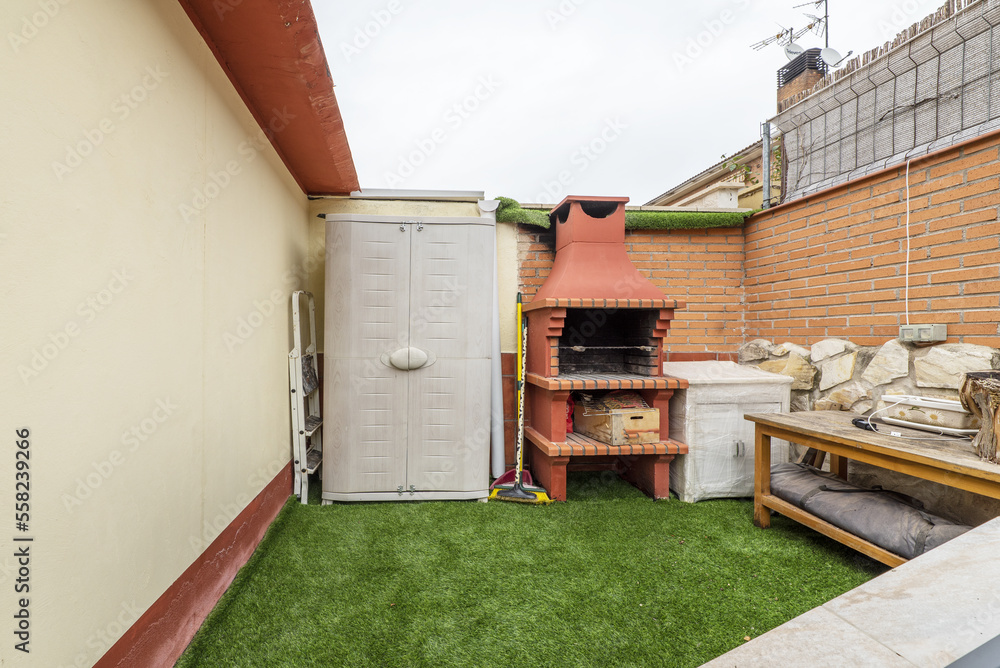Terrace of a single-family home with artificial grass, resin cabinet and built-in barbecue grill Terrace of a single-family home with artificial grass, resin cabinet and built-in barbecue grill