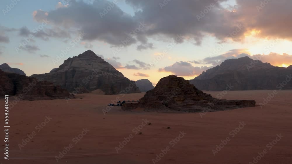 Panoramic sunset view of Wadi Rum desert in Jordan with clouds moving over flat sand landscape with mountains in background, Panoramic sunset view of Wadi Rum desert in Jordan with clouds moving over flat sand landscape with mountains in background,