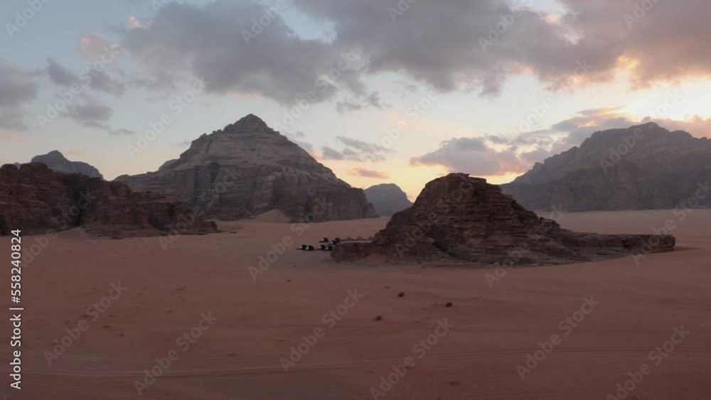 Panoramic sunset view of Wadi Rum desert in Jordan with clouds moving over flat sand landscape with mountains in background, Panoramic sunset view of Wadi Rum desert in Jordan with clouds moving over flat sand landscape with mountains in background,