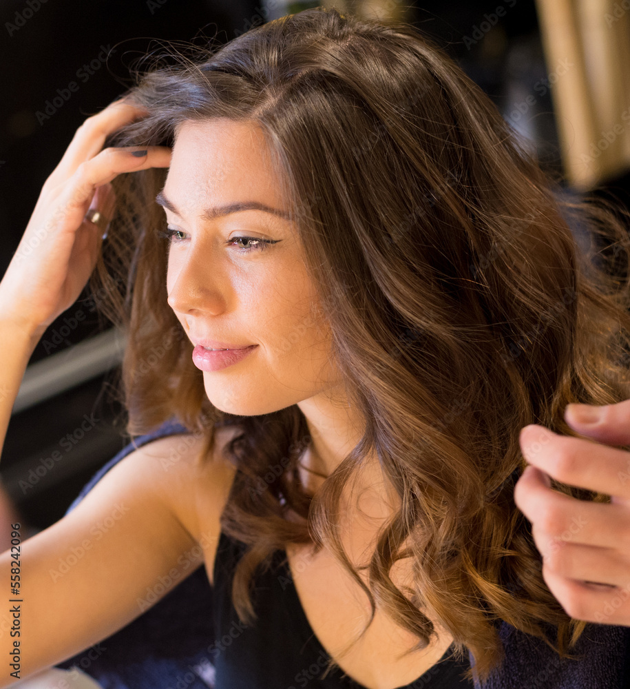 Fototapeta premium Young woman getting a new hairstyle from a hairdresser in the modern hair salon