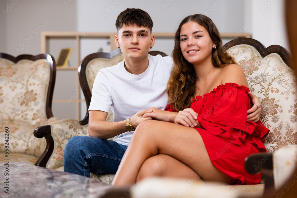 Portrait of a smiling young married couple in an apartment, sitting on the sofa