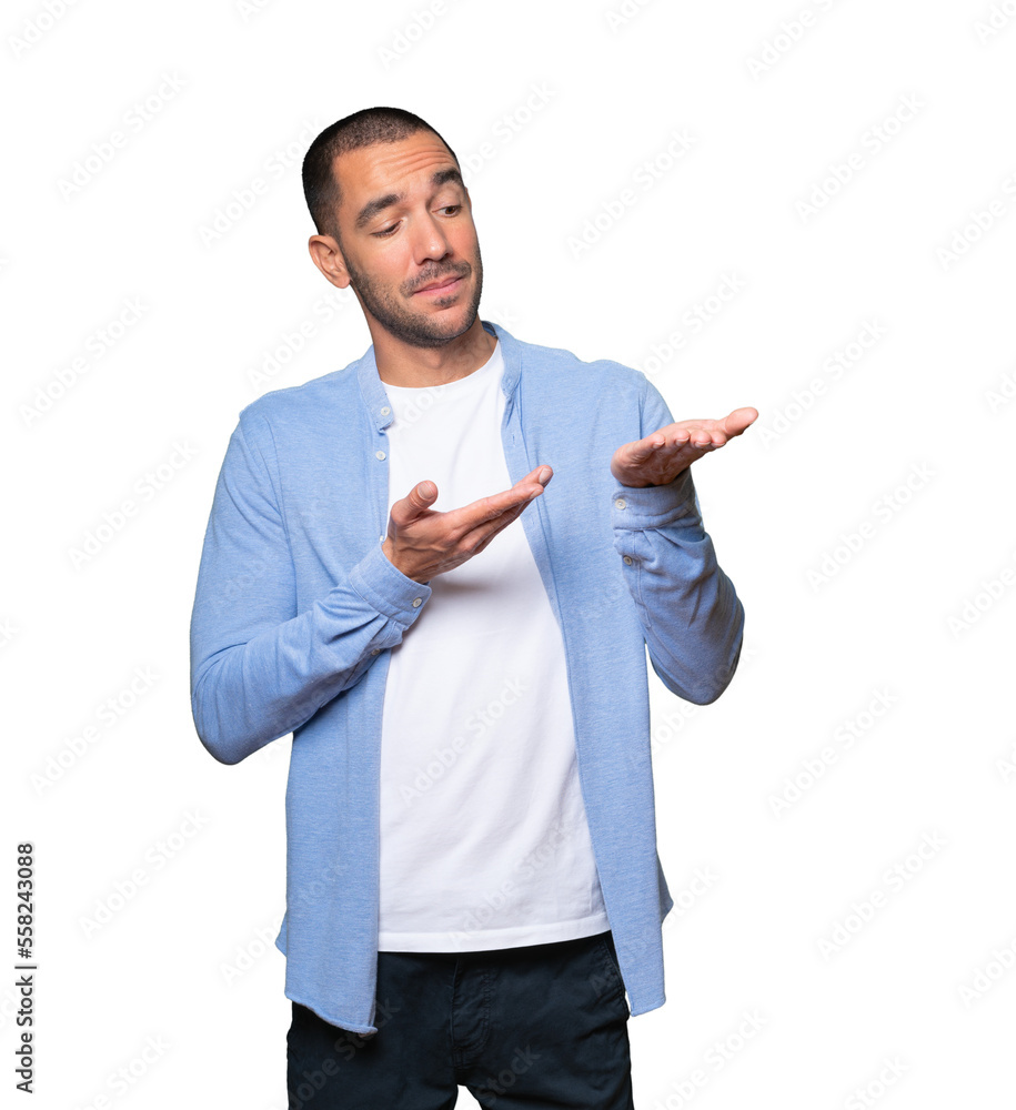 Doubtful young man holding something with his hand Doubtful young man holding something with his hand