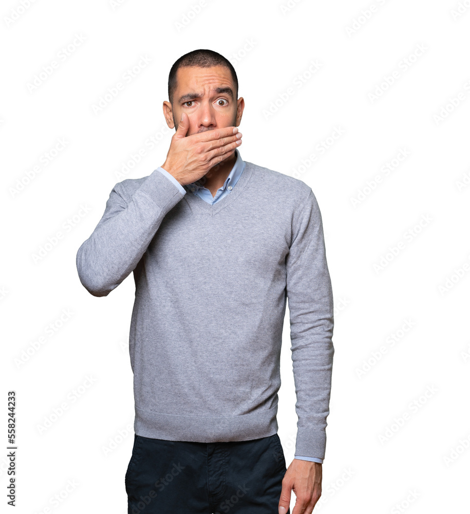 Young man covering his mouth with his hands Young man covering his mouth with his hands