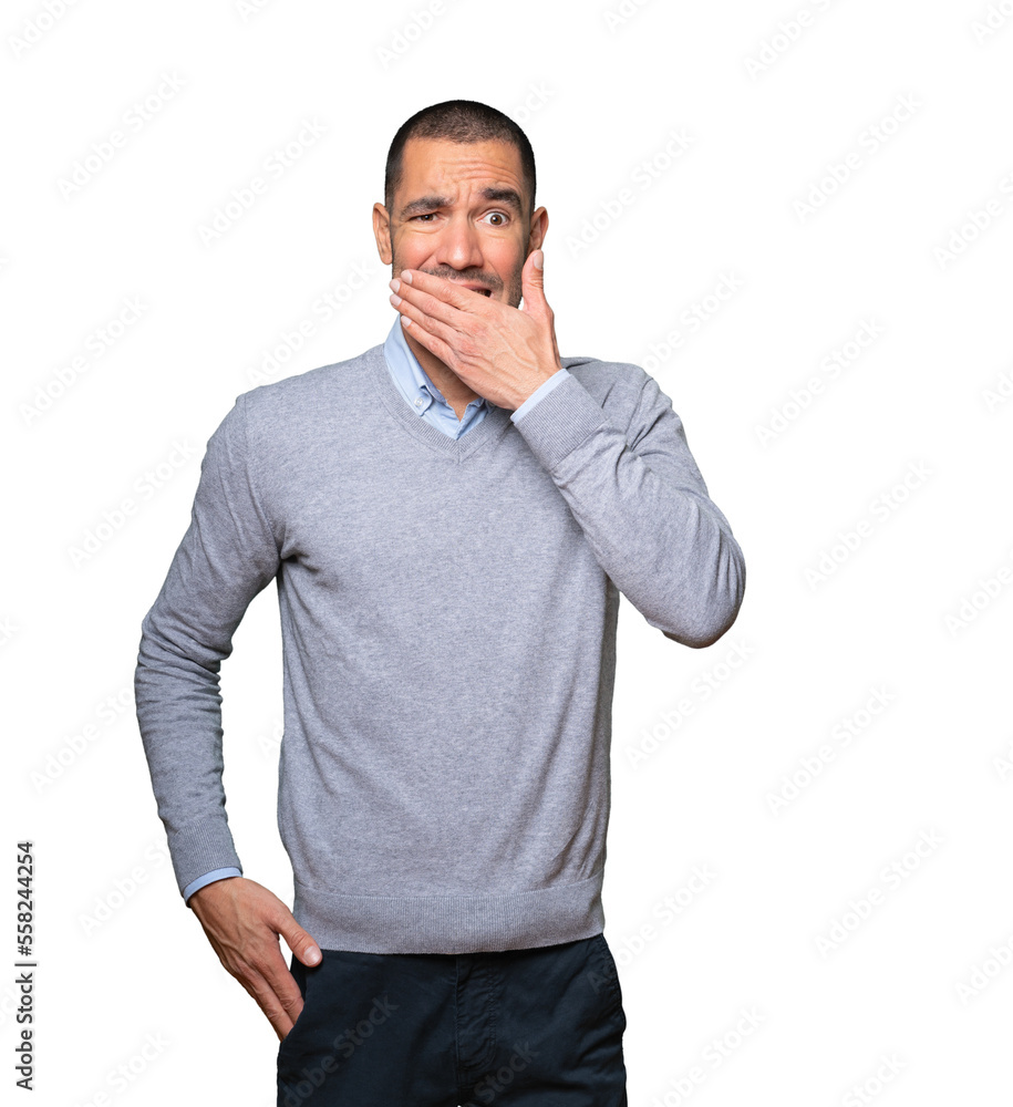 Young man covering his mouth with his hands Young man covering his mouth with his hands
