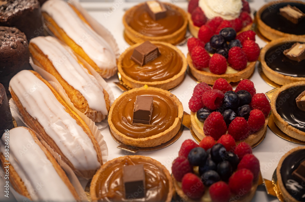 Assortment of french fresh baked sweet pastry with fresh fruits and berries in confectionery shop