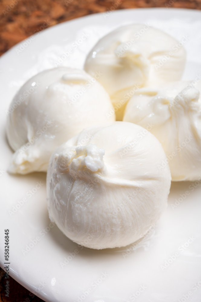 Eating of fresh handmade soft Italian cheese from Puglia, white balls of burrata or burratina cheese made from mozzarella and cream filling Eating of fresh handmade soft Italian cheese from Puglia, white balls of burrata or burratina cheese made from mozzarella and cream filling