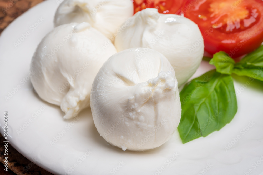Eating of fresh handmade soft Italian cheese from Puglia, white balls of burrata or burratina cheese made from mozzarella and cream filling Eating of fresh handmade soft Italian cheese from Puglia, white balls of burrata or burratina cheese made from mozzarella and cream filling