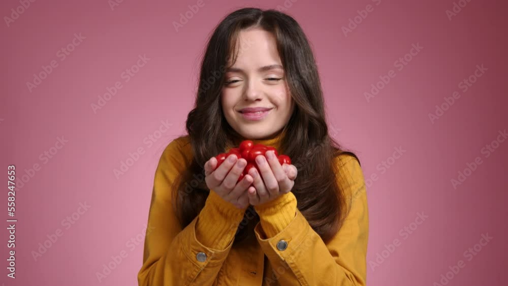 Close-up shot of a teenage girl with a positive facial expression. Portrait of a smiling woman holding tasty cherry tomatoes. High quality 4k footage Close-up shot of a teenage girl with a positive facial expression. Portrait of a smiling woman holding tasty cherry tomatoes. High quality 4k footage