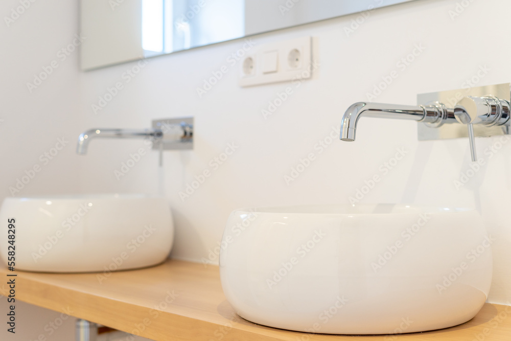 Fototapeta premium Modern washbasins on a wooden board in an illuminated bathroom. High quality photo