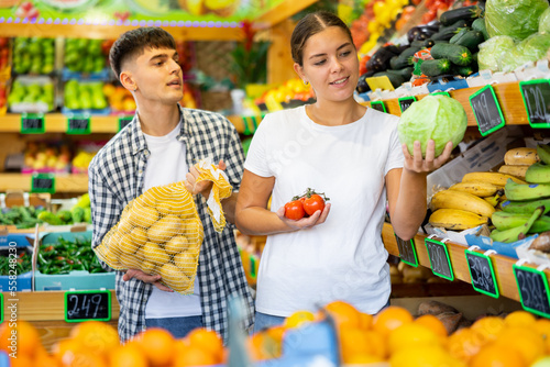 Young husband and wife choose fresh vegetables together in a grocery supermarket