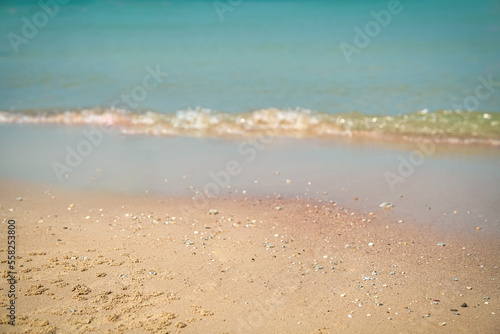 Sand with blurred waves at the background. Sandy beach, summer vacation. Copy space.