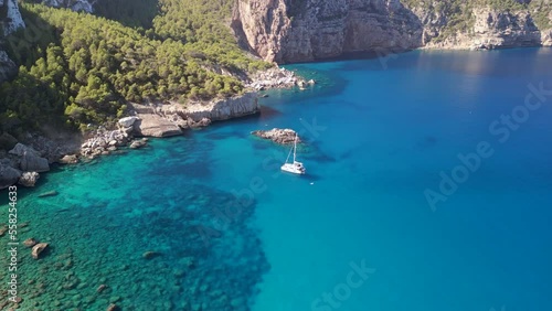 White sailboat, idyllic bay Smooth aerial view flight drone of ibiza Aubarca bay photo